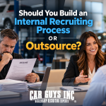 Two car dealership managers, one reviewing resumes and the other interviewing a candidate.